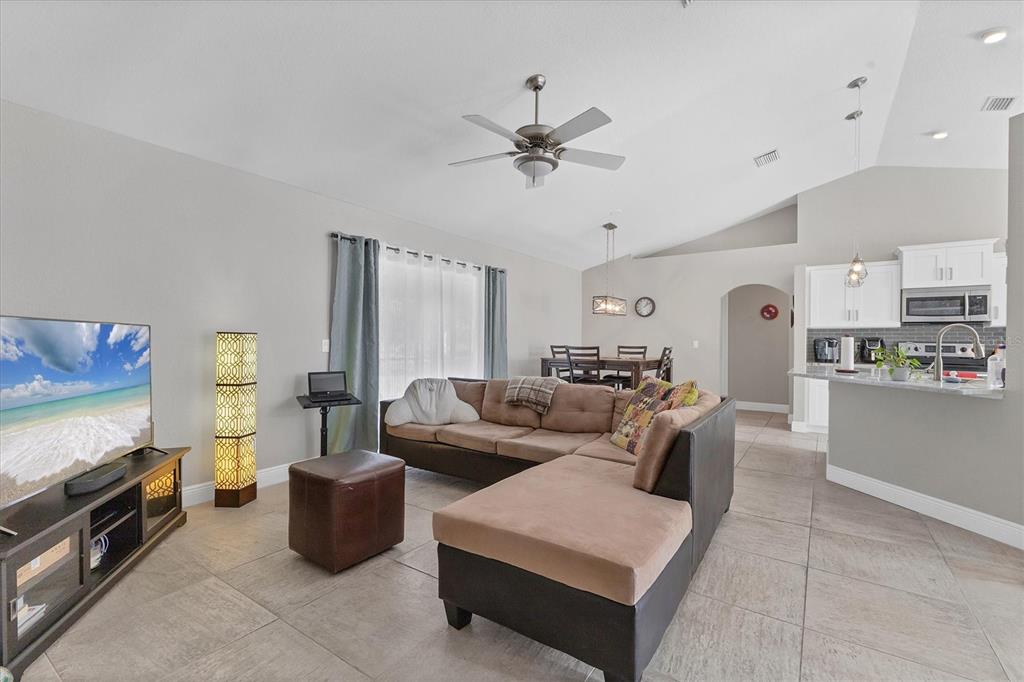 A living room with tile floors, a sectional sofa, and an open kitchen — 7380 MERONI BOULEVARD, NORTH PORT, FL