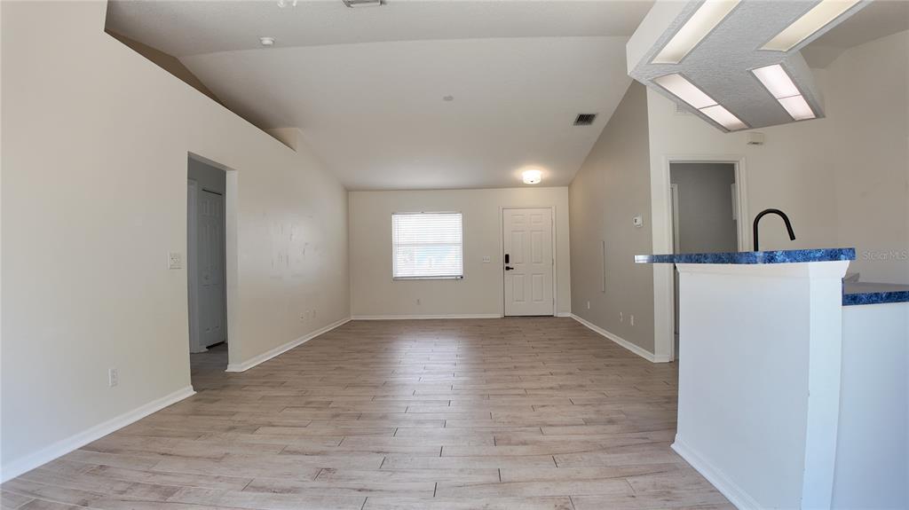 An open-concept living area features light wood-look flooring, vaulted ceilings, and a kitchen breakfast bar — 4915 BARCELONA AVENUE, SARASOTA, FL