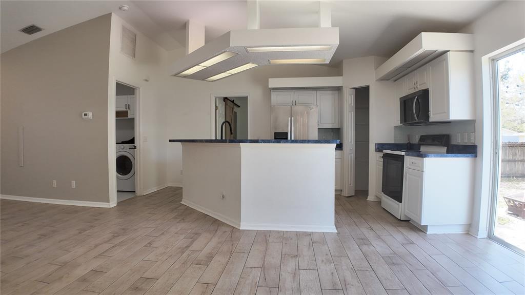 A kitchen with white cabinets, blue countertops, stainless steel appliances, and wood-look tile flooring — 4915 BARCELONA AVENUE, SARASOTA, FL
