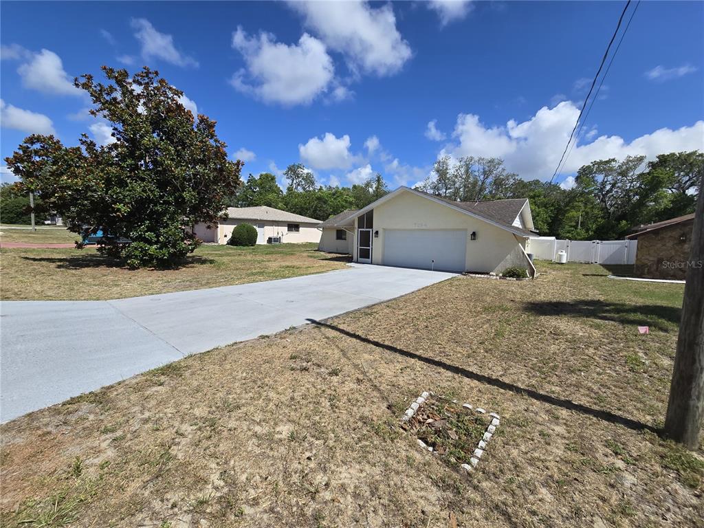 A light-colored single-story house with a two-car garage and a large front yard — 7264 LINDHURST STREET, SPRING HILL, FL