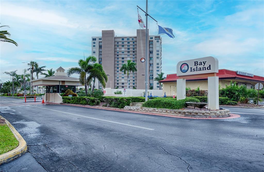 The entrance to the Bay Island community features a guardhouse, signage, and a tall building — 7400 SUN ISLAND DRIVE S UNIT 709, SOUTH PASADENA, FL