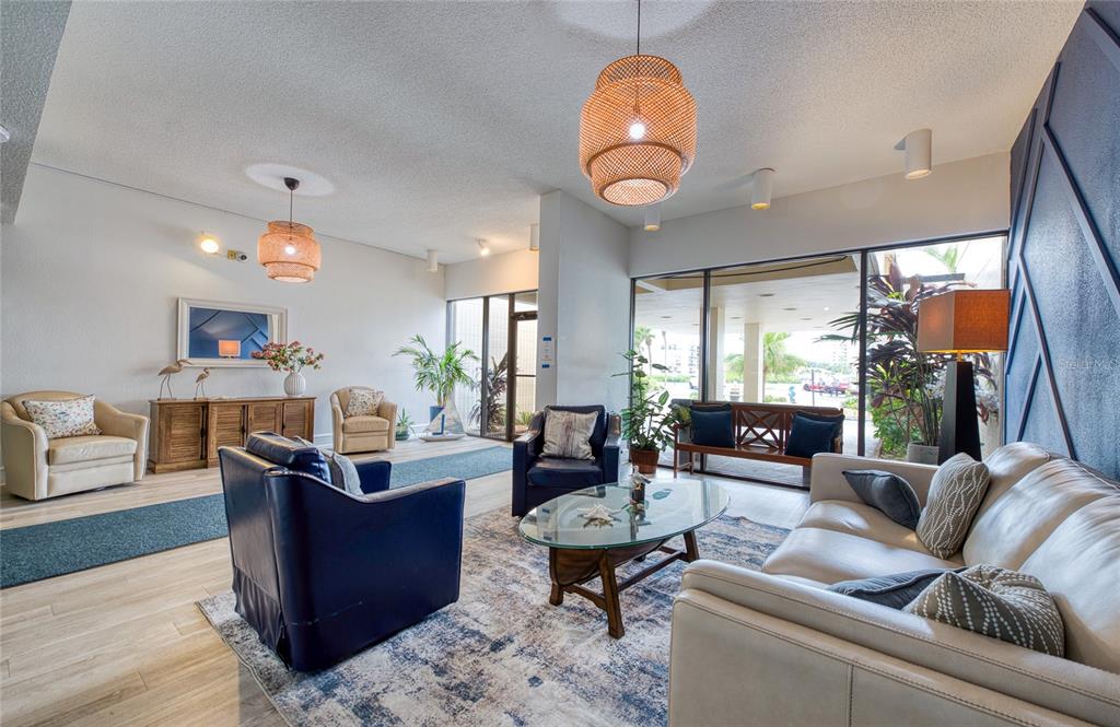A bright lobby features a seating area with a leather sofa, armchairs, and woven pendant lights — 7400 SUN ISLAND DRIVE S UNIT 709, SOUTH PASADENA, FL