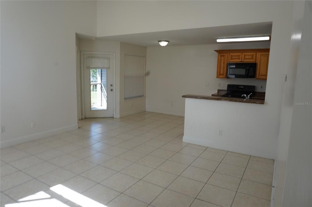 An open-concept living area features light tile flooring, a kitchen pass-through, and a glass door — 2584 GRASSY POINT DRIVE UNIT 204, LAKE MARY, FL