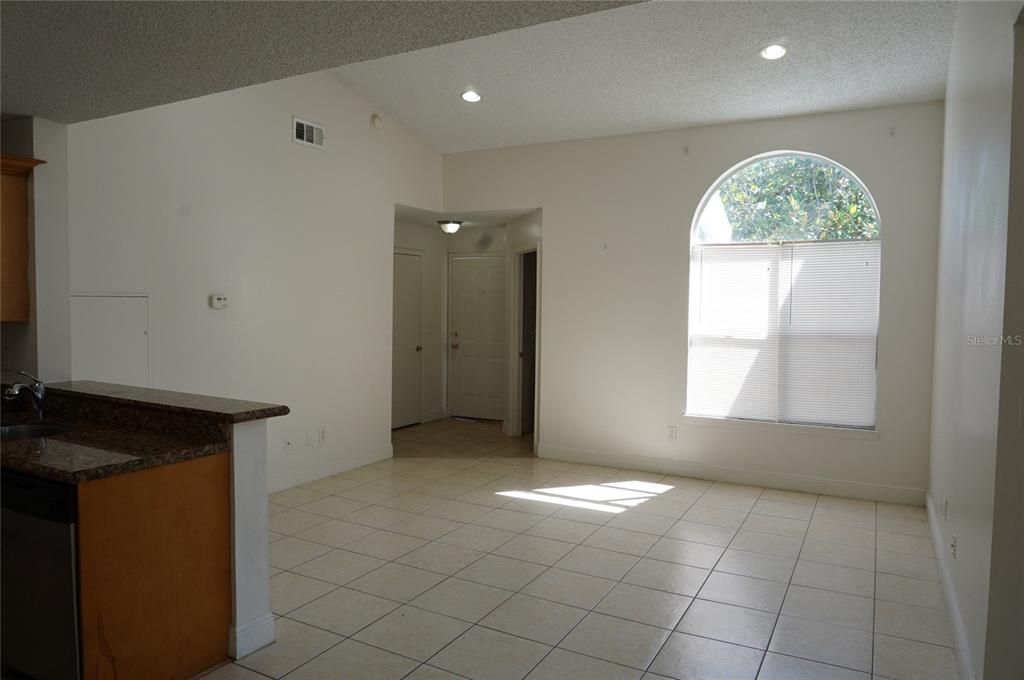 A living area with tile flooring, a vaulted ceiling, and an arched window — 2584 GRASSY POINT DRIVE UNIT 204, LAKE MARY, FL