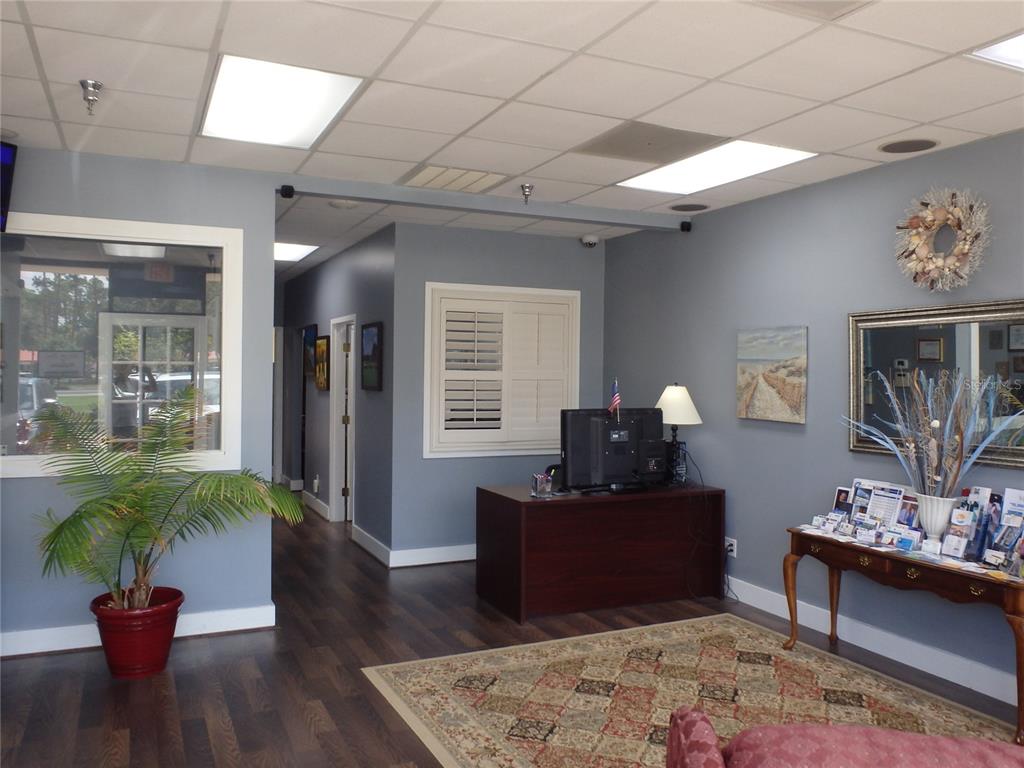 A reception area features a dark wood desk, a patterned rug, and blue-painted walls — 4984 PALM COAST PARKWAY NW UNIT 7, PALM COAST, FL