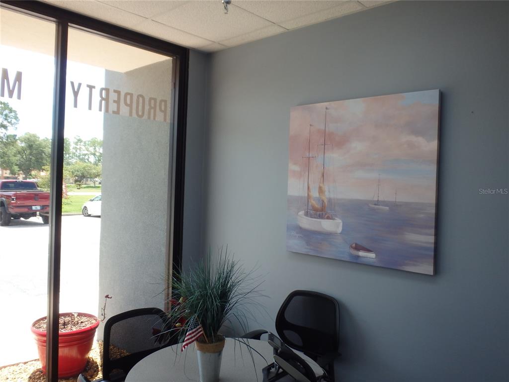 An office interior features a small round table, two chairs, and a sailboat wall painting — 4984 PALM COAST PARKWAY NW UNIT 7, PALM COAST, FL