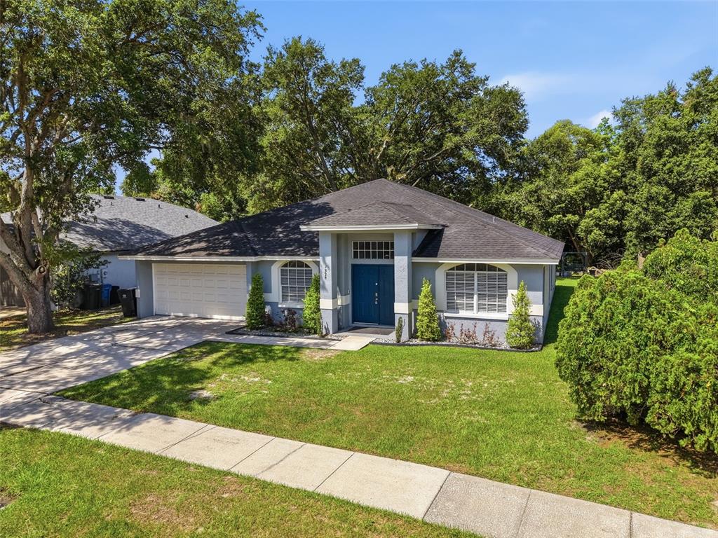A single-story house with a blue front door, arched windows, and a two-car garage — 1328 GANGPLANK DRIVE, VALRICO, FL