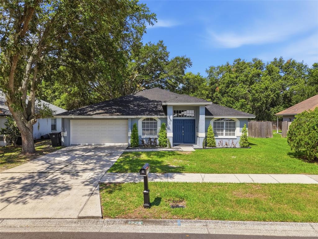 A single-story house with a blue front door, arched windows, and a two-car garage — 1328 GANGPLANK DRIVE, VALRICO, FL