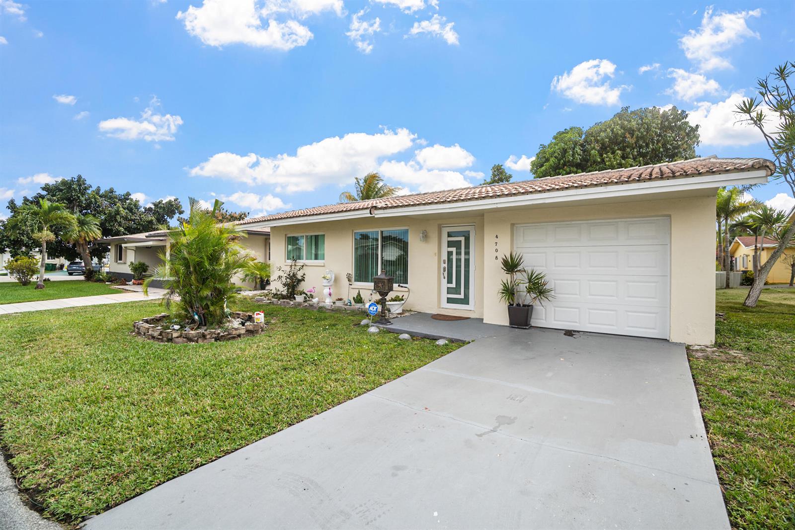 A single-story house with a beige exterior, a white garage door, and a front lawn — 4708 NW 49th Drive, Tamarac FL 33319, TAMARAC, FL