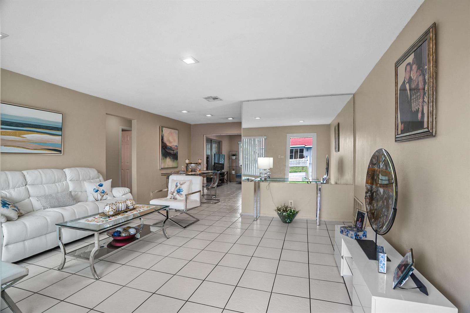 A living room features white tile flooring, a white leather sofa, and a mirrored wall — 4708 NW 49th Drive, Tamarac FL 33319, TAMARAC, FL