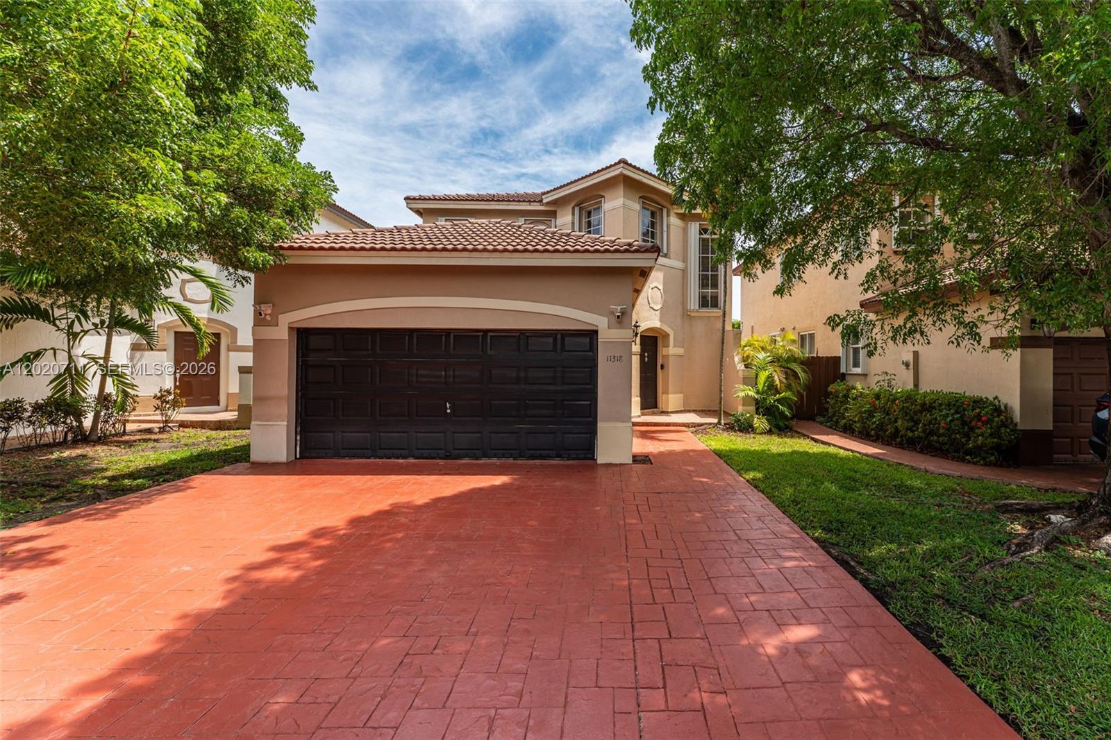 A two-story house with a red-tiled roof, a black garage door, and a paved driveway — 11318 NW 44th Ter, Doral FL 33178, DORAL, FL
