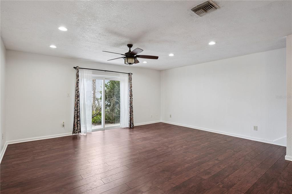 A spacious room features dark wood-look flooring, white walls, a ceiling fan, and sliding glass doors — 193 LEWFIELD CIRCLE, WINTER PARK, FL