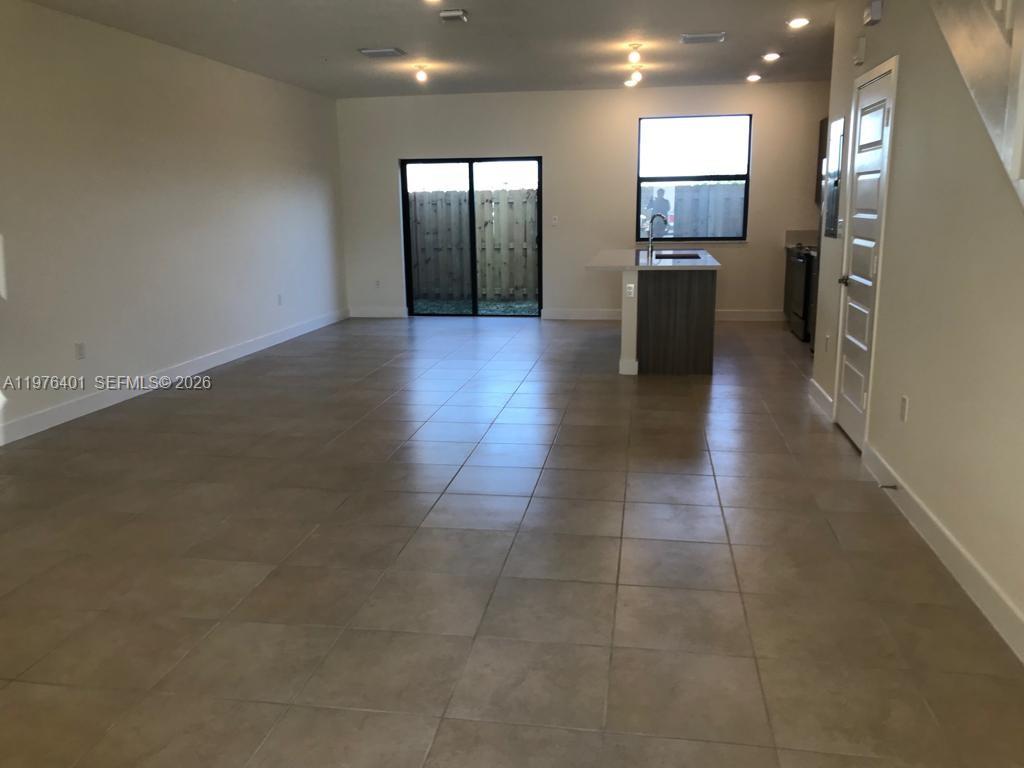 An open-concept living and kitchen area features large beige floor tiles and sliding glass doors — 10431 NW 82nd St # 5, Doral FL 33178, DORAL, FL