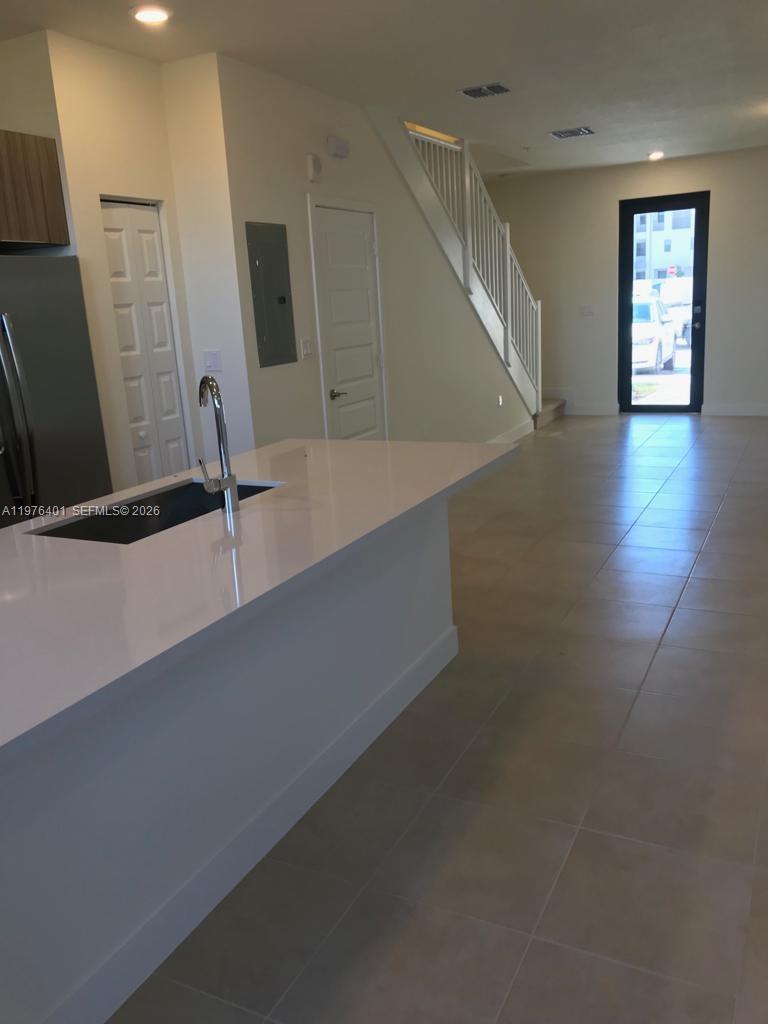 A kitchen island with a sink sits in an open-plan room with tiled floors — 10431 NW 82nd St # 5, Doral FL 33178, DORAL, FL