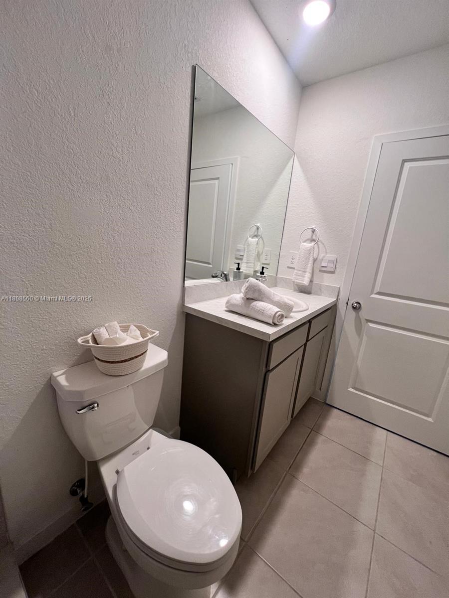 A bathroom features a toilet, a vanity with a mirror, and a tiled floor — 245 NE 3rd Ct, Florida City FL 33034, FLORIDA CITY, FL