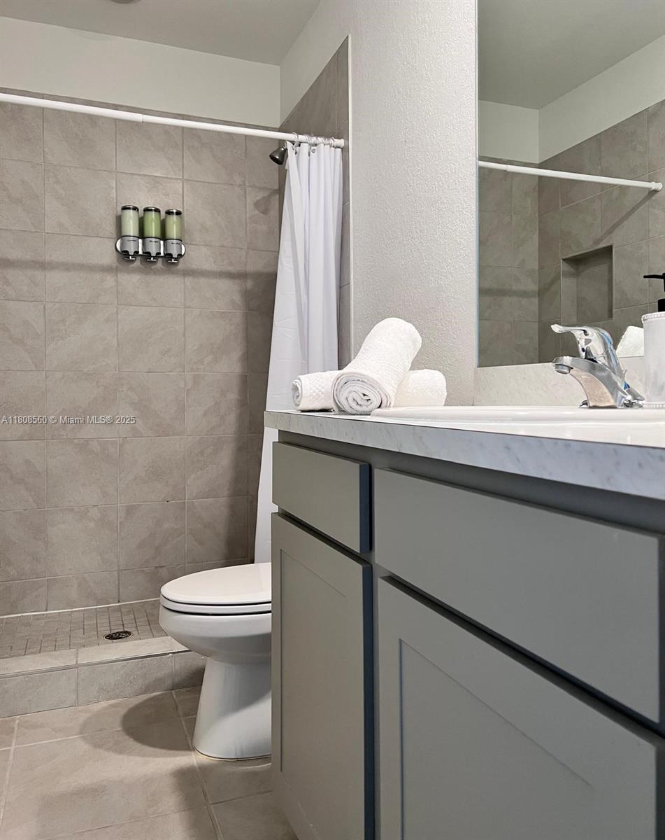 A bathroom features a gray vanity, a tiled walk-in shower, and a white toilet — 245 NE 3rd Ct, Florida City FL 33034, FLORIDA CITY, FL