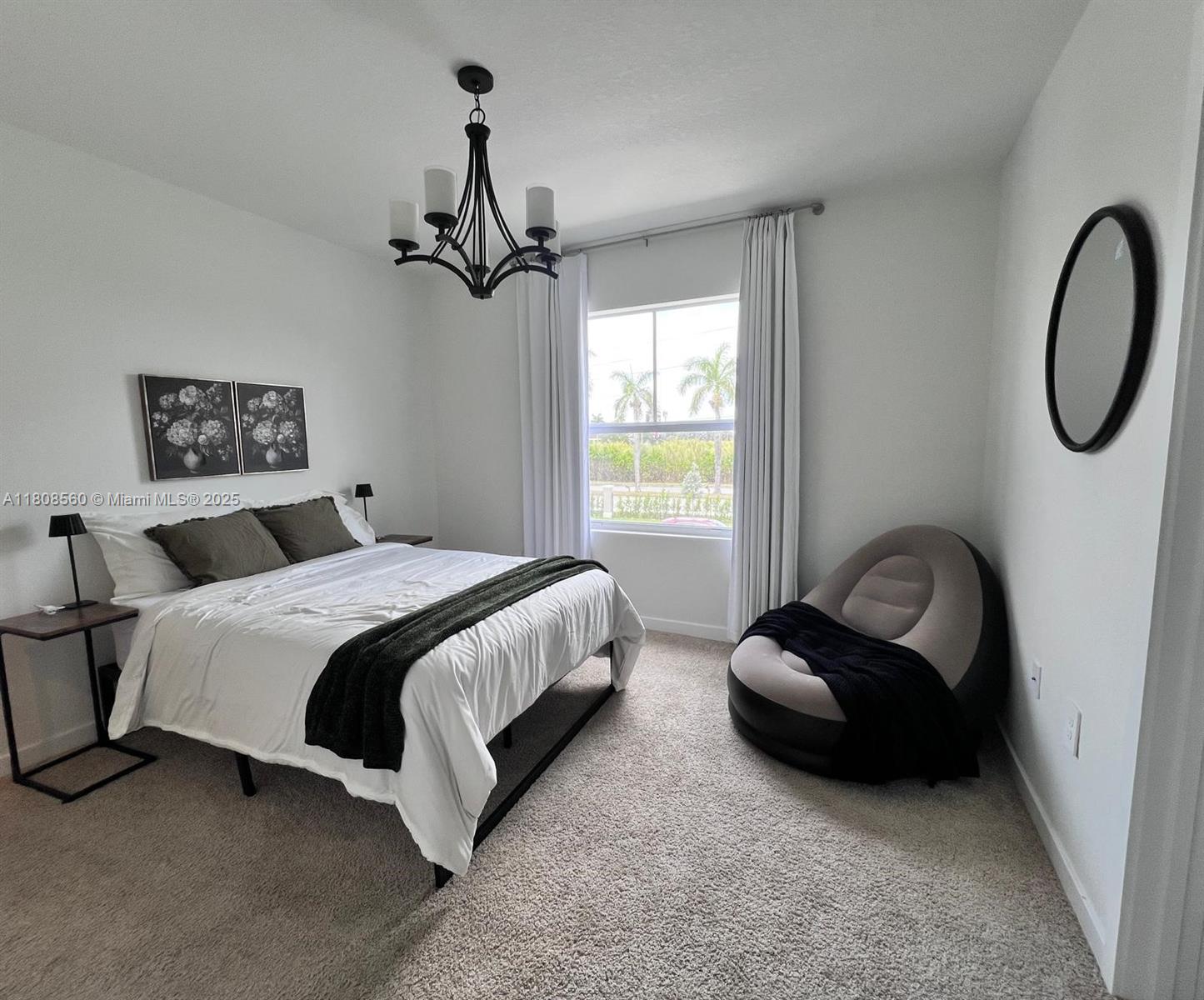 A bedroom features a bed with dark pillows, a chandelier, and a circular wall mirror — 245 NE 3rd Ct, Florida City FL 33034, FLORIDA CITY, FL