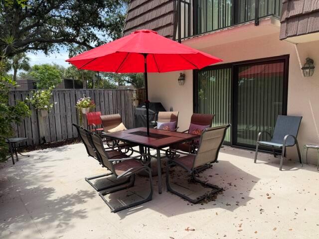 A patio features a dining set with a red umbrella and several chairs — 1604 16th Court, Jupiter FL 33477, JUPITER, FL