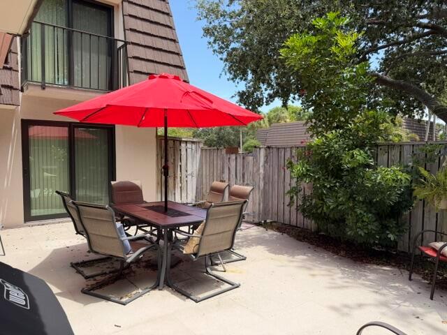 A patio features a dining set with a red umbrella and a wooden privacy fence — 1604 16th Court, Jupiter FL 33477, JUPITER, FL