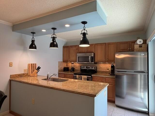 A kitchen features a granite-topped island, wooden cabinets, stainless steel appliances, and pendant lighting — 1604 16th Court, Jupiter FL 33477, JUPITER, FL