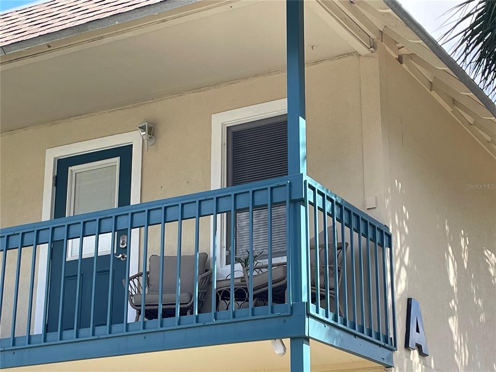 A balcony with blue railings and furniture is attached to a beige building exterior — 30 SE VALARE LANE UNIT 205A, CRYSTAL RIVER, FL