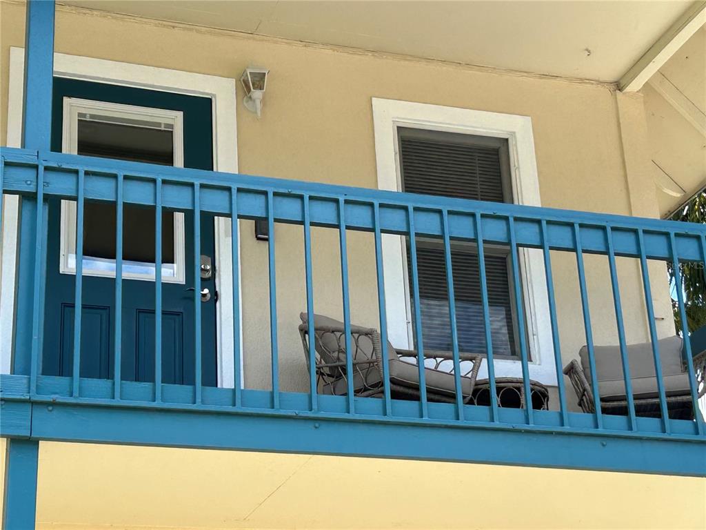 A blue metal railing encloses a balcony with a dark door and a window — 30 SE VALARE LANE UNIT 205A, CRYSTAL RIVER, FL