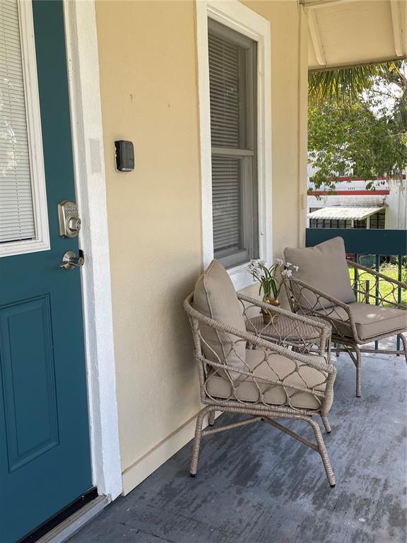 A covered porch features a teal door, two wicker chairs, and a small side table — 30 SE VALARE LANE UNIT 205A, CRYSTAL RIVER, FL