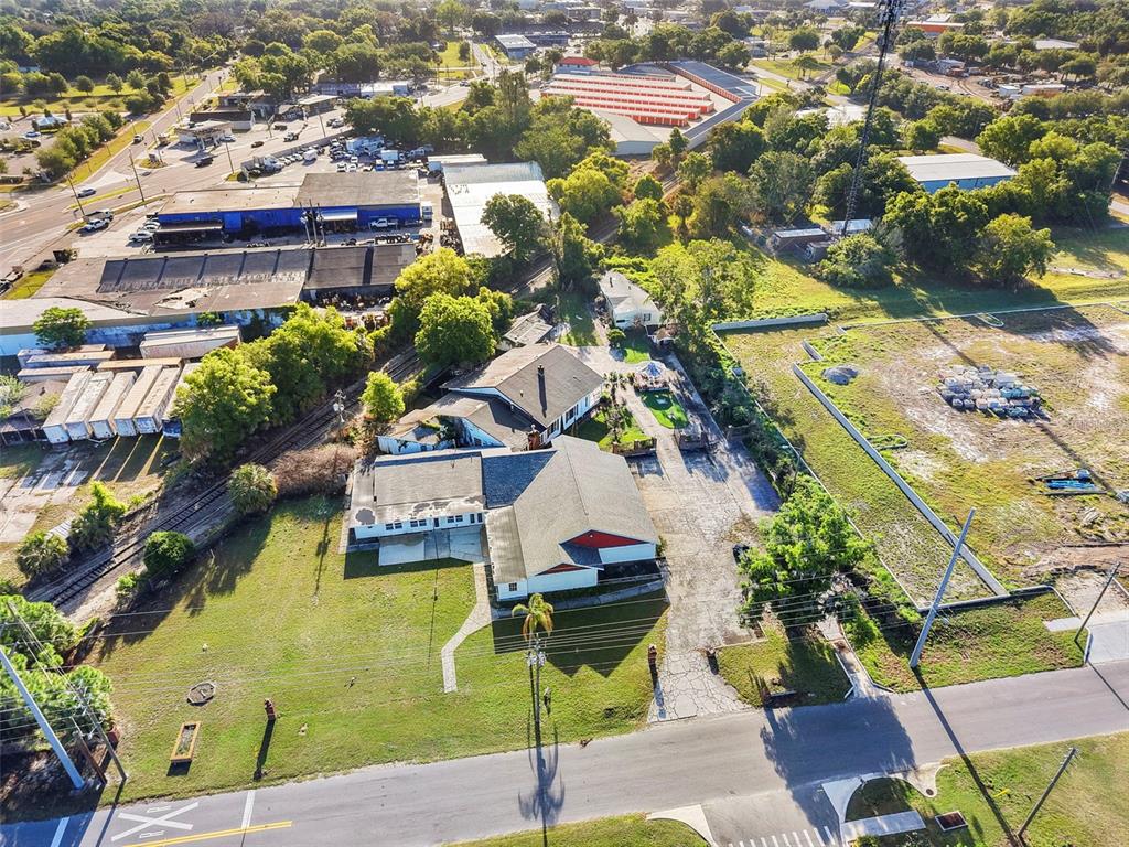 An aerial view shows a commercial building with a large parking lot near railroad tracks — 227 S HAWTHORNE AVENUE, APOPKA, FL