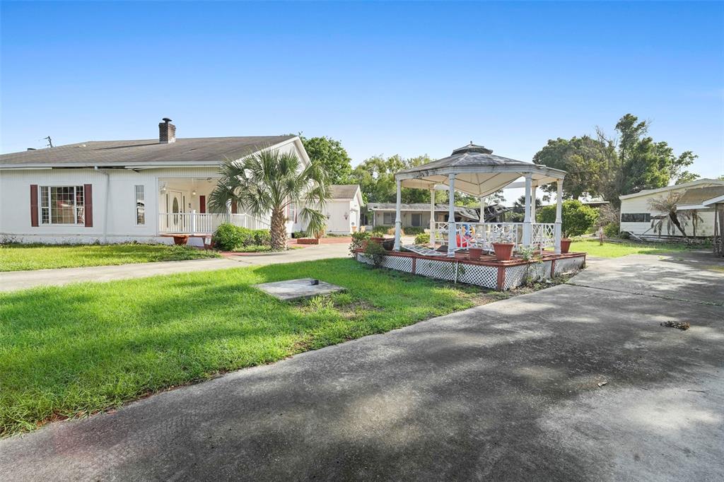 A white house with a gazebo sits on a grassy lot with a concrete driveway — 227 S HAWTHORNE AVENUE, APOPKA, FL