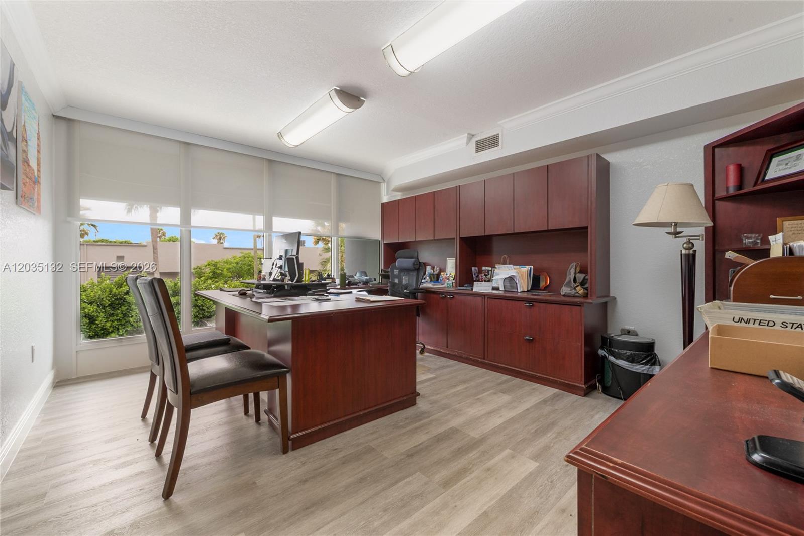 A home office features a large wooden desk, matching cabinetry, and light wood-look flooring — 16155 SW 117th Ave # B21, Miami FL 33177, MIAMI, FL