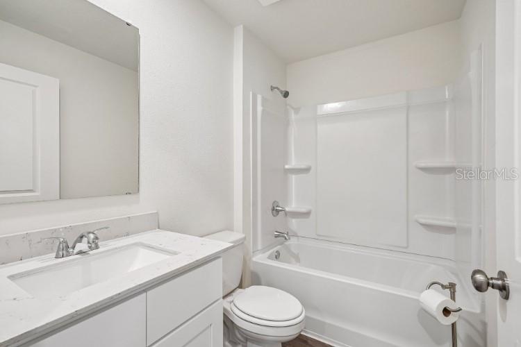 A bathroom features a white vanity with a marble countertop, a toilet, and a tub-shower combo — 14246 NW 162ND PLACE, ALACHUA, FL