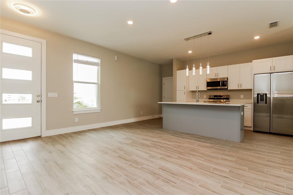 A kitchen with a gray island and white cabinets opens into a living area — 260 GLADIOLA COURT, KISSIMMEE, FL