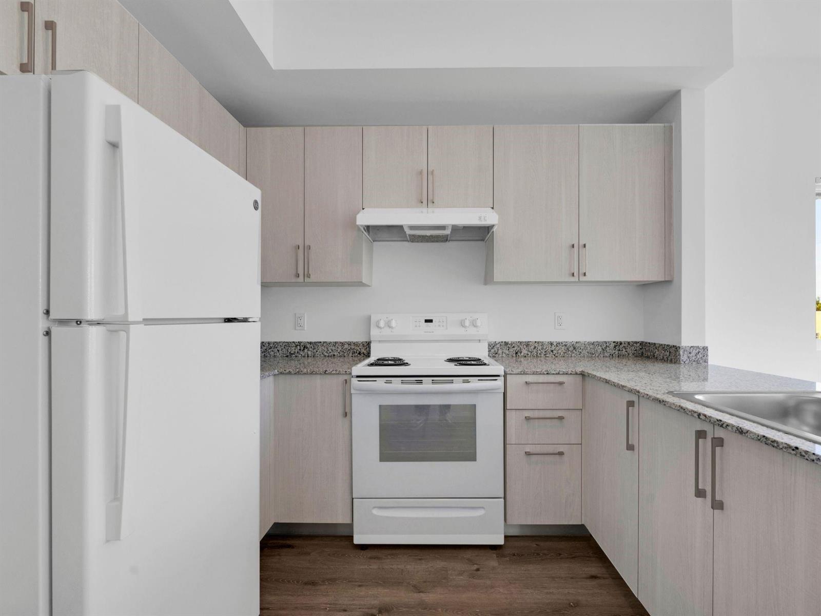 A kitchen features light wood cabinets, white appliances, and granite countertops over dark wood flooring — 2130 NW 37th Street, Miami FL 33142, MIAMI, FL