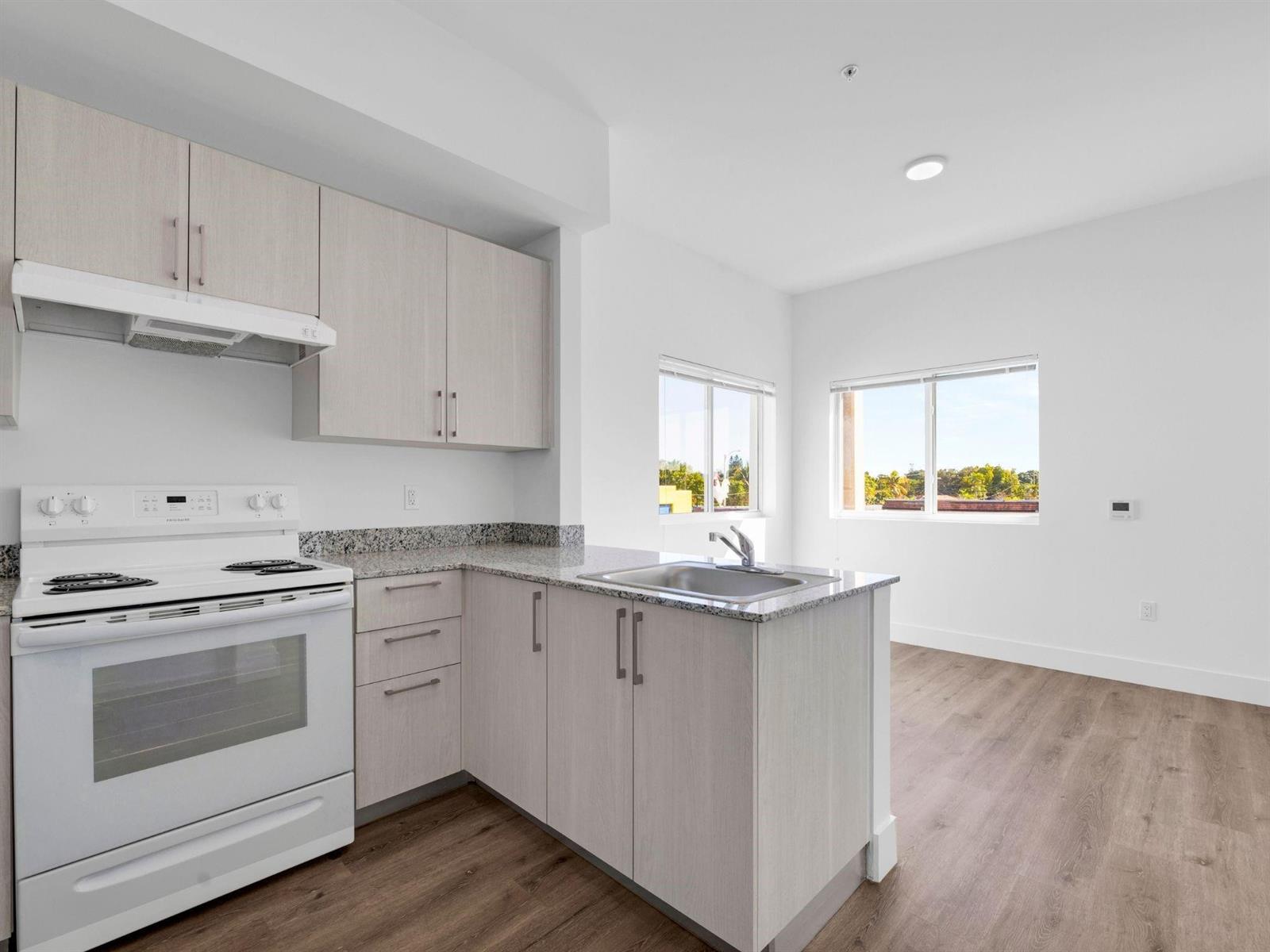 A kitchen with light wood cabinets, granite countertops, and a white stove overlooks a room — 2130 NW 37th Street, Miami FL 33142, MIAMI, FL