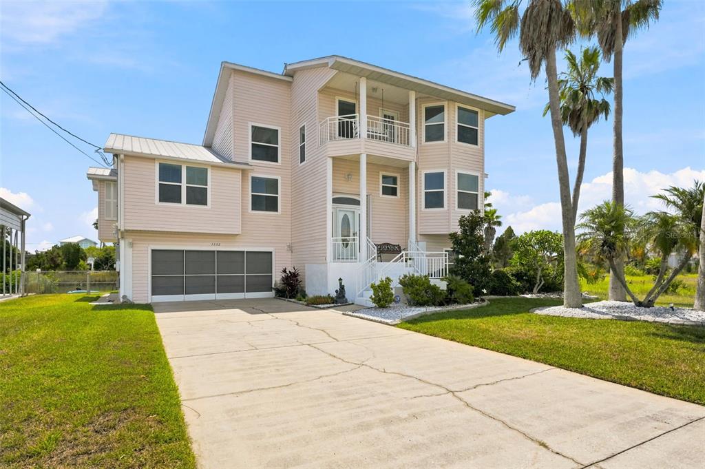 An aerial view shows waterfront houses at sunset with a dock and metal carport — 3342 TURKS CAP DRIVE, HERNANDO BEACH, FL