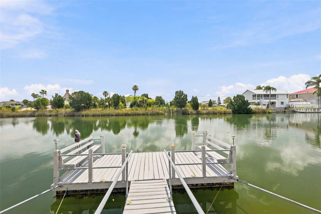 A three-story light pink house with a concrete driveway and palm trees in the yard — 3342 TURKS CAP DRIVE, HERNANDO BEACH, FL