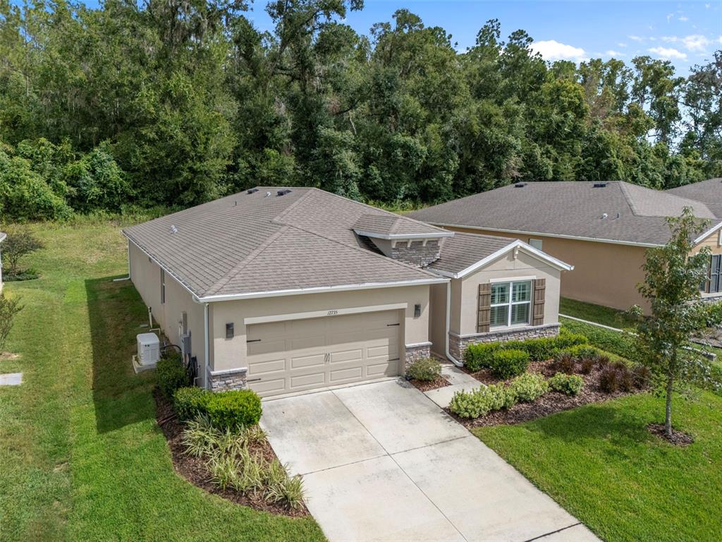 An aerial view of a tan single-story house with a two-car garage and landscaping — 12735 EASTPOINTE DRIVE, DADE CITY, FL