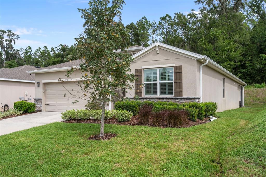 A single-story house with a beige stucco exterior, a two-car garage, and a front lawn — 12735 EASTPOINTE DRIVE, DADE CITY, FL