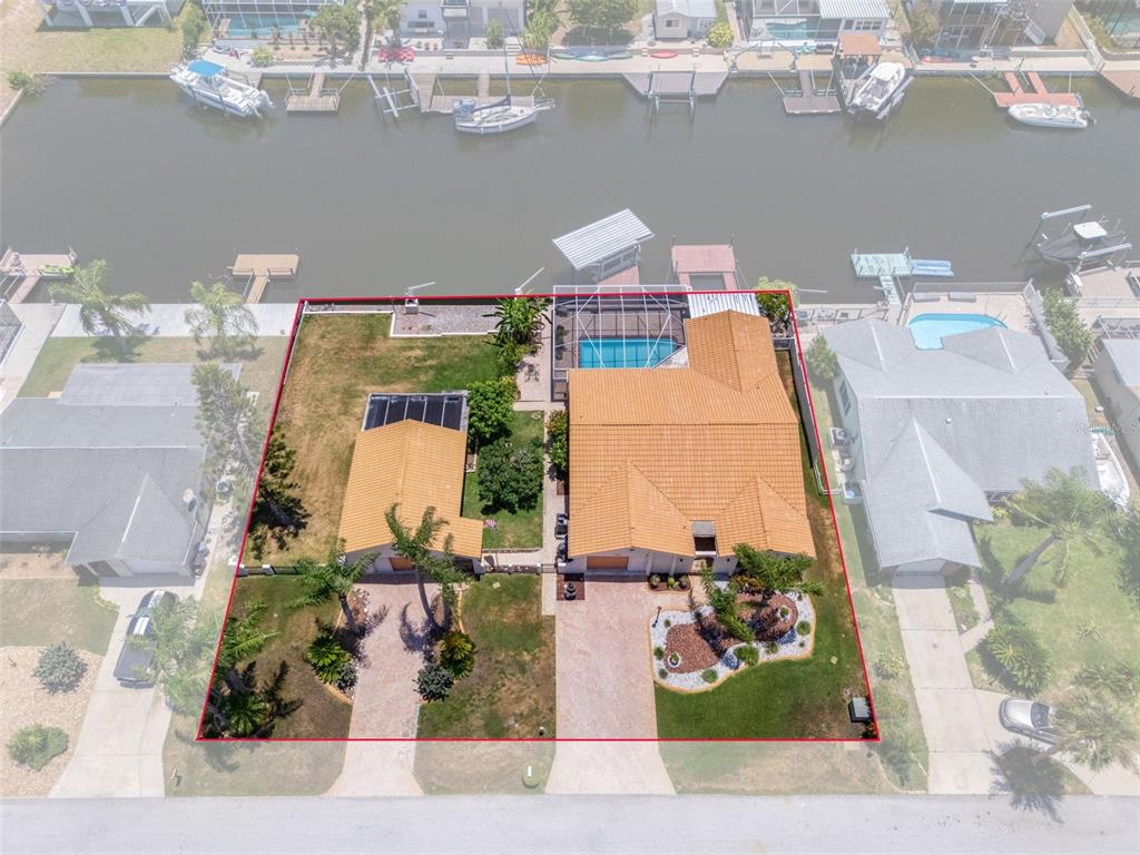 An aerial view shows a waterfront house with a pool, detached garage, and boat dock — 15602 CENTURY DRIVE, HUDSON, FL