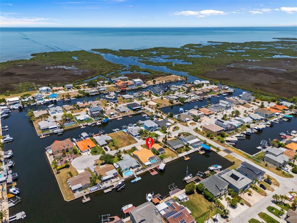 An aerial view shows a waterfront house with a pool, marked by a red pin — 15602 CENTURY DRIVE, HUDSON, FL