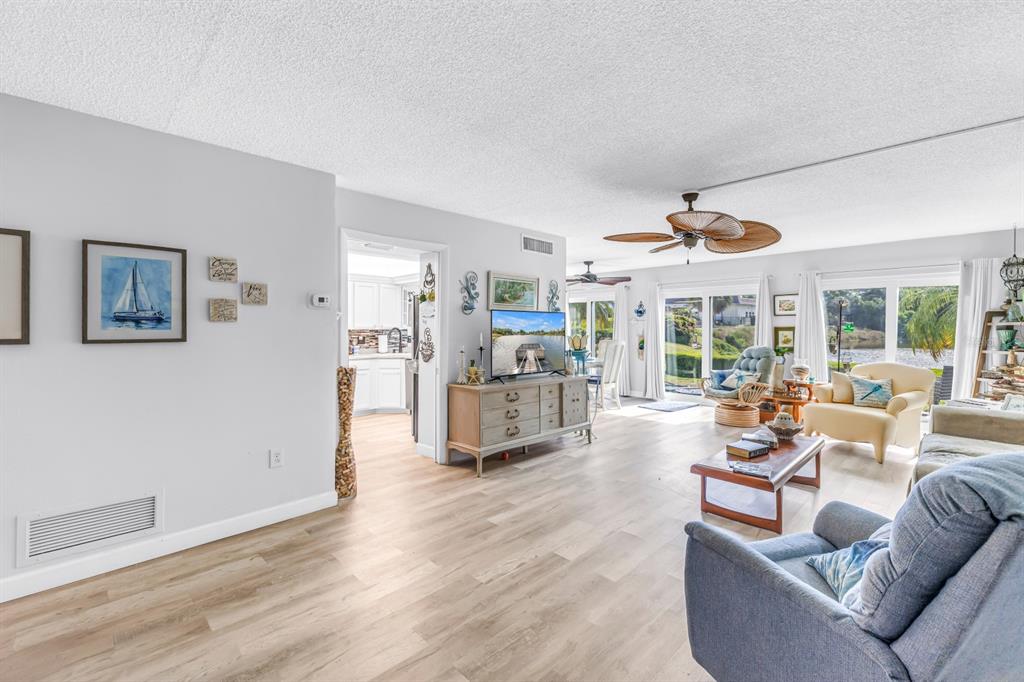A living room with light wood flooring, a ceiling fan, and a view of water — 1655 S HIGHLAND AVENUE UNIT J187, CLEARWATER, FL