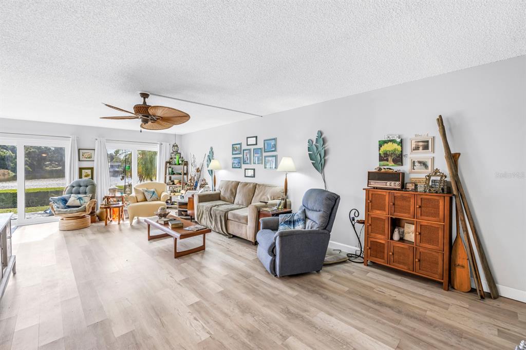 A living room with light wood flooring, a ceiling fan, and a view of water — 1655 S HIGHLAND AVENUE UNIT J187, CLEARWATER, FL