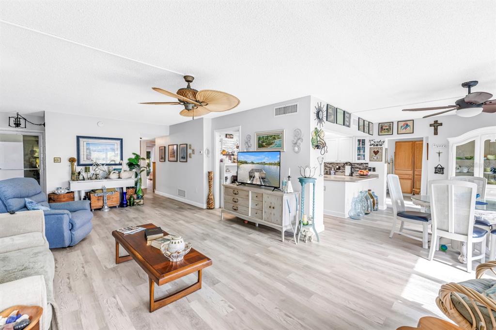 A living room with light wood-look flooring, a ceiling fan, and an open-concept kitchen area — 1655 S HIGHLAND AVENUE UNIT J187, CLEARWATER, FL