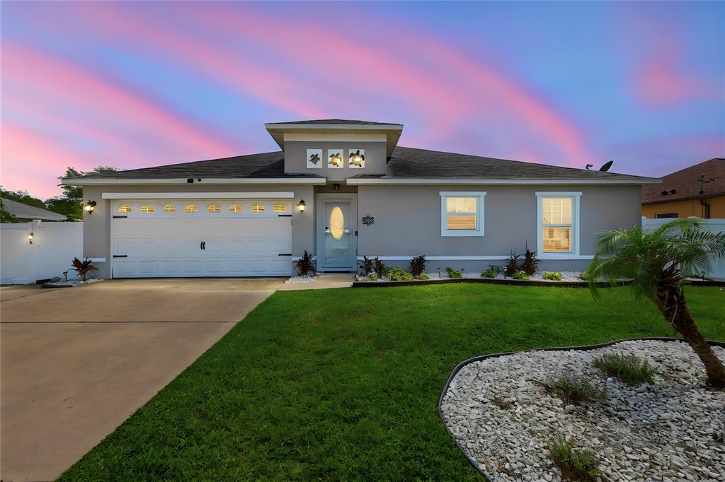 A single-story gray house with a two-car garage and a landscaped front yard — 36 ROYAL PALM LANE, PALM COAST, FL