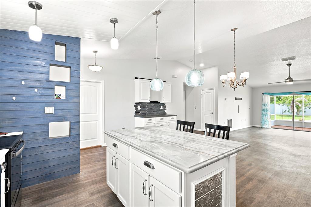 A kitchen features a white island with a marble countertop and a blue wood-paneled wall — 36 ROYAL PALM LANE, PALM COAST, FL