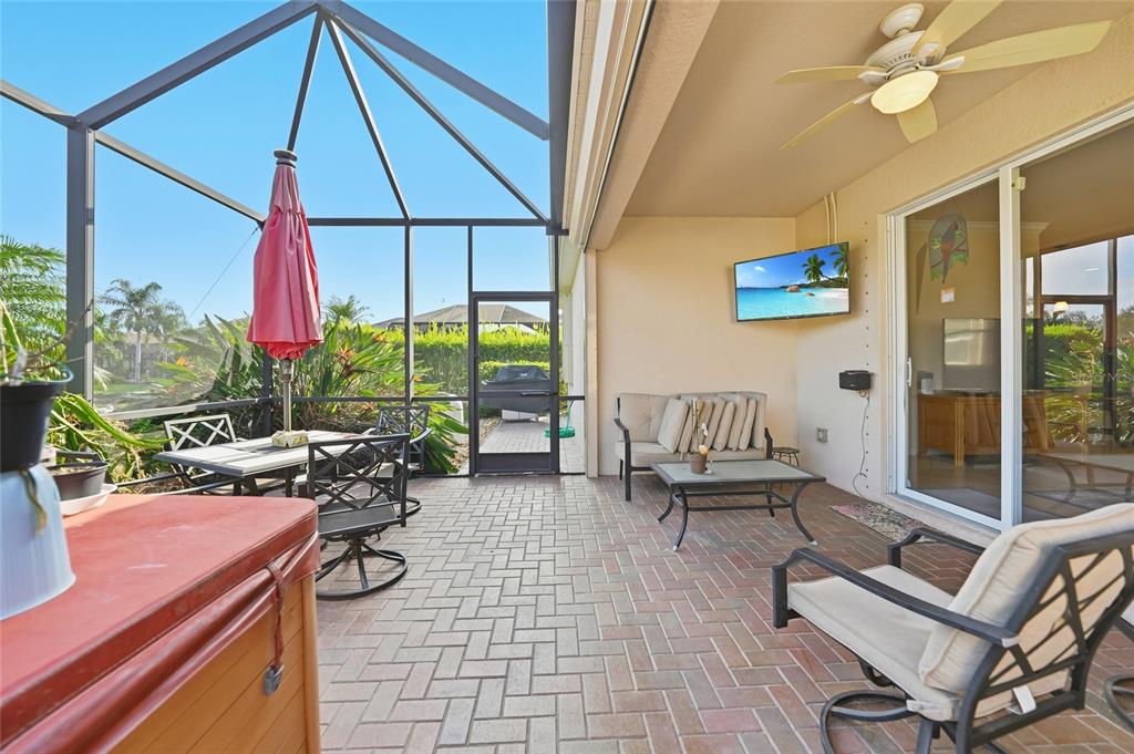 A screened-in patio features brick pavers, outdoor furniture, a ceiling fan, and a wall-mounted television — 11720 SPOTTED MARGAY AVENUE, VENICE, FL