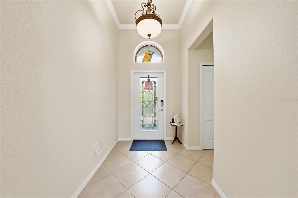 An entryway features a tiled floor, a decorative front door, and a hanging light fixture — 11720 SPOTTED MARGAY AVENUE, VENICE, FL