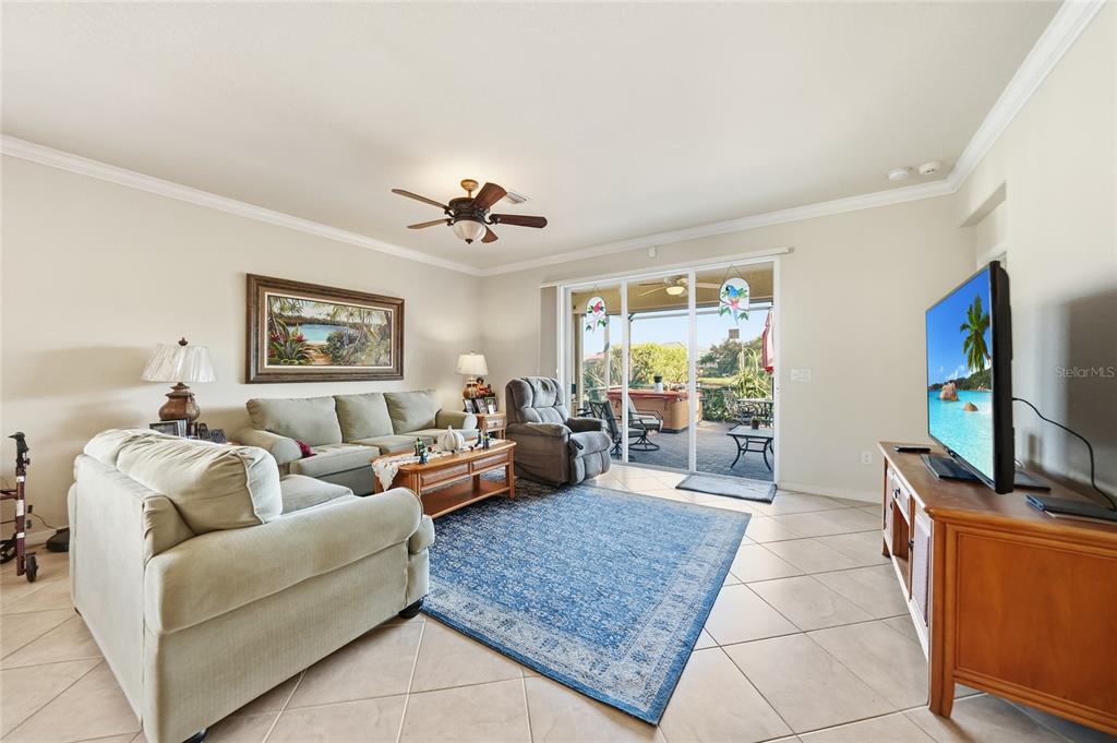 A living room features tile floors, a blue area rug, a sofa, and sliding glass doors — 11720 SPOTTED MARGAY AVENUE, VENICE, FL