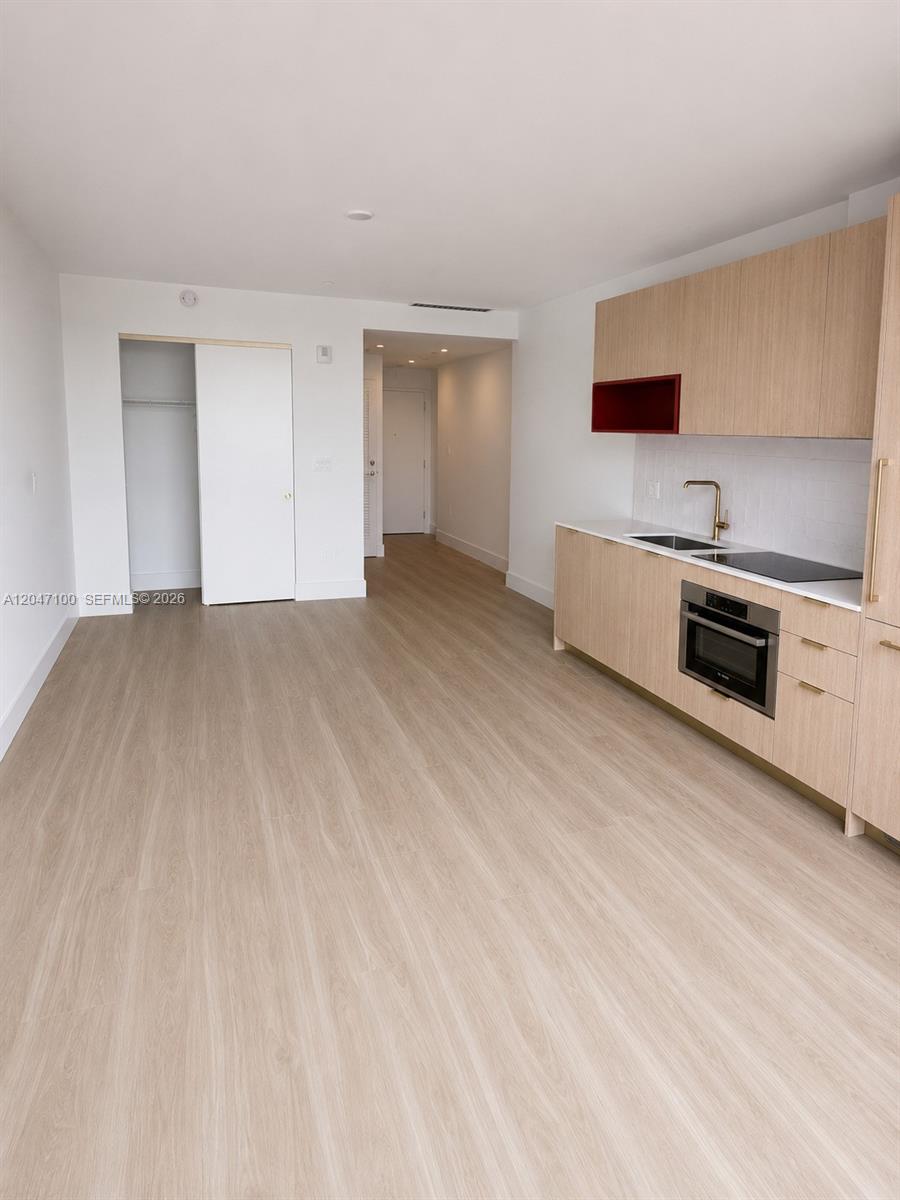 This studio apartment features light wood flooring, a modern kitchenette, and a white closet — 90 NE 32nd St # 1126, Miami FL 33127, MIAMI, FL