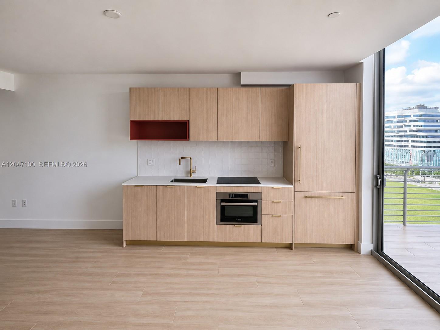 A modern kitchen features light wood cabinets, a red open shelf, and a balcony view — 90 NE 32nd St # 1126, Miami FL 33127, MIAMI, FL